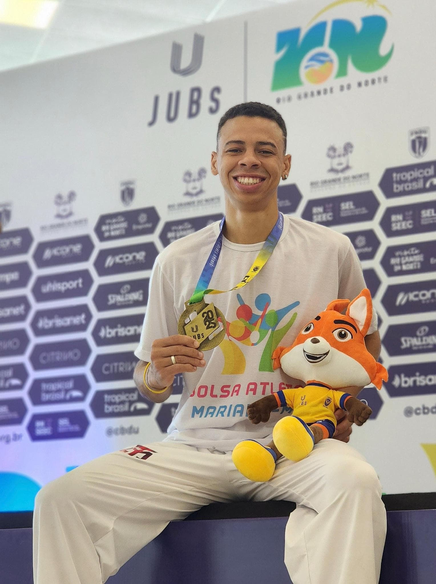 Luiz Augusto com a medalha dos Jogos Universitários Brasileiros e o mascote do evento