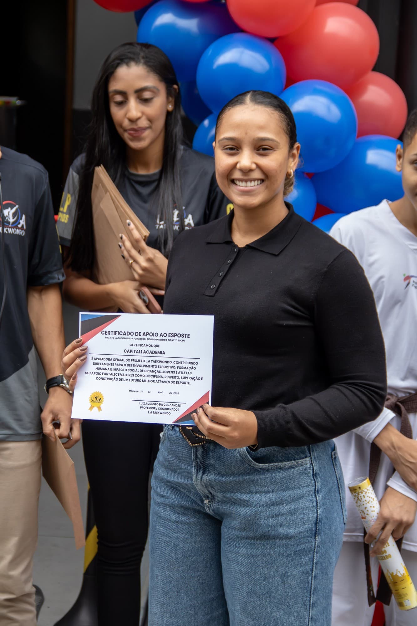 Apoiadora segurando o certificado de apoio ao esporte do projeto L.A Taekwondo